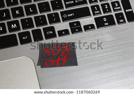 Advertising message about Black Friday on black post it: reminder on silver laptop.
