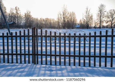 old wooden fence in garden at countryside with morning light and snow around it in winter