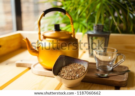 Arabian spiced coffee still life with teapot, glass coffee cup, tea spoon, wooden table and a lamp on a coffee shop environment with natural light.