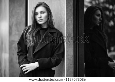 Beautiful girl in a coat in business downtown of the cloudy
