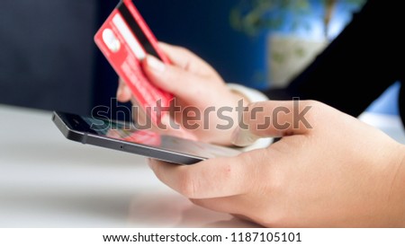 Closeup photo of young woman using smartphone holding credit card