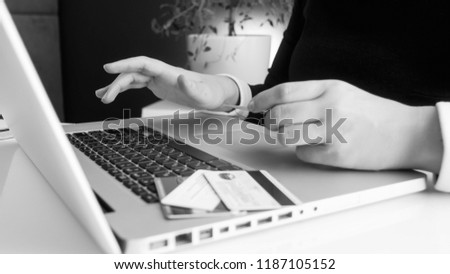Black and white photo of oyung woman making online payments with credit cards