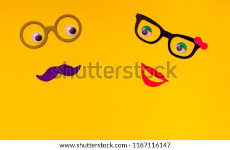 Couples concept with paper photo boot props smilling and looking at eachother on an yellow background