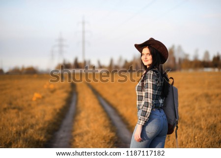 A young girl is traveling around the city hitchhiking. A beautiful young girl went on vacation. A female student in a cowboy hat on the road.
