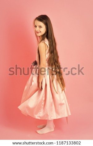 Little girl with long hair on pink background. Small girl child model in beautiful dress. Childhood, look, happiness, hairstyle. Kid fashion, hairdresser, birthday. Beauty and fashion, punchy pastels.