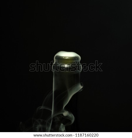 Closeup view of one new open full champagme wive sweet or dry drink green glass bottle with beautiful white smoke for celebration christmas or new year in studio on black background, square picture