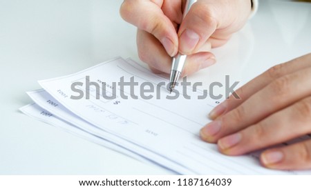 Closeup photo of young businesswoman filling personal banking cheque