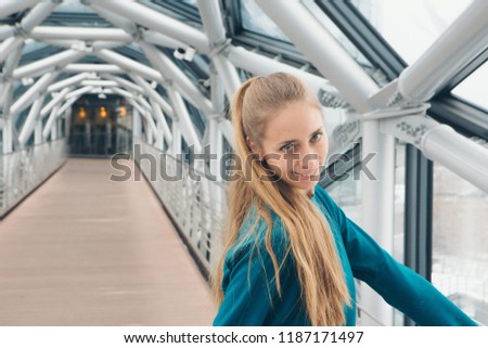a woman stands on a bridge inside a glass tunnel