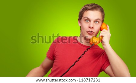 Portrait of a young man talking on vintage phone on green background
