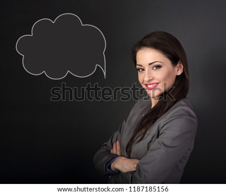 Beautiful business woman in grey suit looking happy with cloud bubble above on dark grey background. Closeup portrait