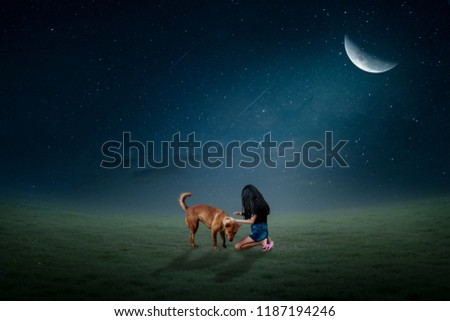 Little girl sitting with dog on the lawn in half a beautiful half moon.