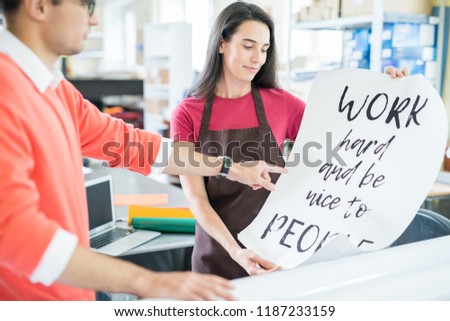Woman and man working in team in printing office and designing modern inspirational poster 