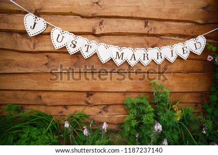 Hanging decorative flags with inscription Just Married. Lettering decoration, wooden wall as background. Text garland on the wall, Wedding invitation card. Vintage wooden background.