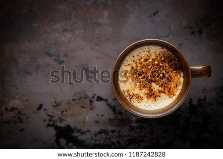 Christmas concept - festive gingerbread man and deer shaped cookies with a cup of cappuccino coffee against dark rustic background. Overhead view