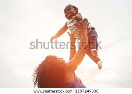 Happy african mother playing with her daughter outdoor - Afro mum and child having fun together - Family, happiness and love concept - Soft focus on woman face Royalty-Free Stock Photo #1187249338