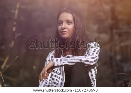 beautiful young woman sitting on a log