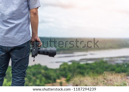 Young man holding a camera on the cliff. Used as a background for travel and tourism.