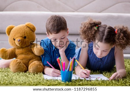 Two kids drawing pictures lying on the door