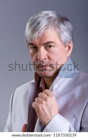Animposing respectable grey-haired man. A handsome imposing respectable grey-haired man wearing a light-colored jacketis looking attentively.