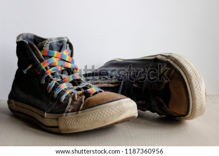Pair of worn vintage blue sneakers with suede soles and rainbow laces. Hipster footwear for long road, travelling and hiking. Closeup photo of old boots representing retro grunge vibes.