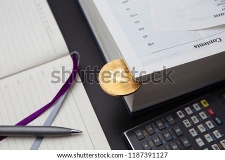 A table with book on the background, calculator and graph in a diary. Learning crypto currency. Concept, a new educational subject