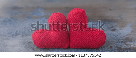 Valentine's Day red knitted wool hearts on concrete background, toned