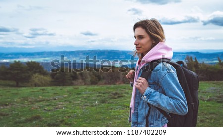 tourist traveler with black backpack standing on green top on mountain, hiker looking on hills and mountain, girl enjoying nature panoramic landscape in trip, relax holiday concept in trekking trip