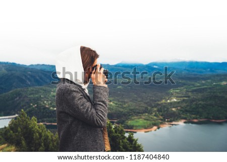 photographer tourist traveler standing on green top on mountain holding in hands digital photo camera, hiker taking click photography, girl enjoy nature panoramic landscape in trip, relax holida