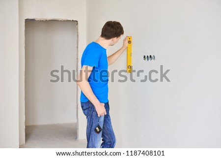 Man using a spirit level to plumb a wall. Home renovation concept