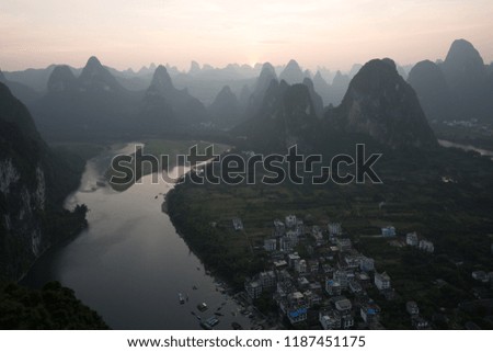 a small fisher town in asia china at dawn day sunrise and night with a lot of hills and mountains