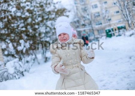 girls play snowballs in yard of kindergarten. Winter background. Games in street in winter. Happy childhood.