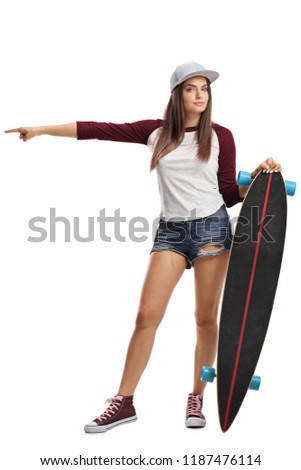 Full length portrait of a young female with skateboard pointing in one direction isolated on white background