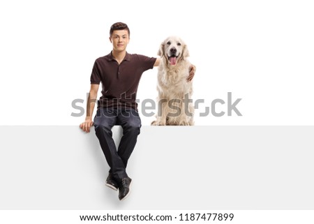 Teenage boy sitting on a panel and hugging a retriever dog isolated on white background
