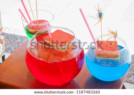 Different color alcoholic and non-alcoholic summer cocktails with pink straws in big glasses on a wooden table on a sunny day