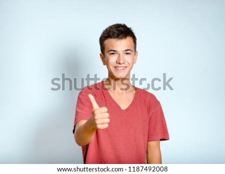 young man shows gesture thumb up, like it, isolated studio photo on background