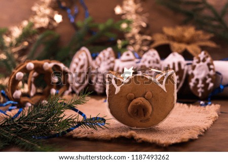 Homemade Christmas cookies in the shape of a pig's head next to Christmas decorations.