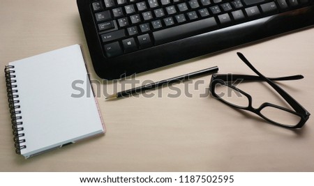 blank open notebook, black glasses, pencil and black keyboard on the desk  