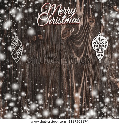 View from above of a Merry Christmas inscription and handmade tree toys on wooden background, greeting card with space for text writing, snow effect