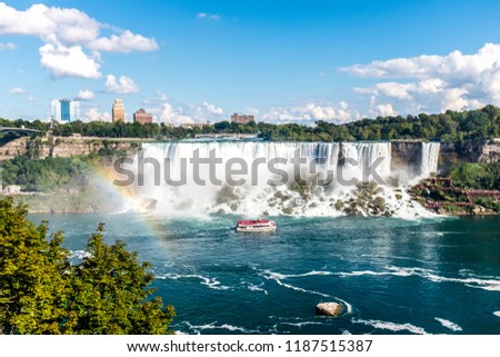 The Maid of the Mist in front of the American part of the Niagara Falls. Followed by a rainbow on the left side of the picture.