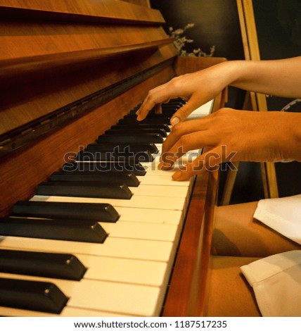 The human hand is pressing on piano key,playing music,for practice,vintage and art tone,blury light around