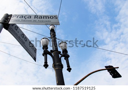 Text in Portuguese means Ramos Square and Cha Viaduct. Street signs and old light pole in downtown of Sao Paulo, brazil. Street Sign on the foreground.
