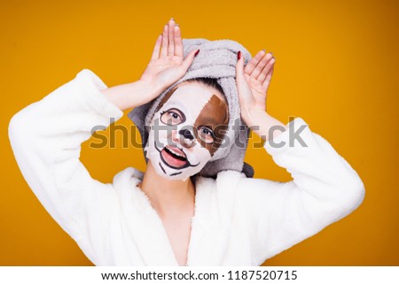 cute girl in white bathrobe posing, on face mask with muzzle of dog