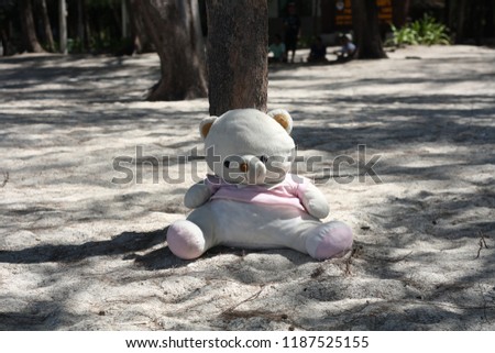 A little teddy bear sitting Under the tree 