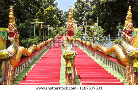 Red staircase decorated with Naga statue in Thai temple...green and sky.