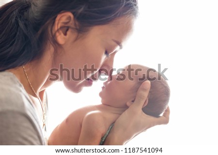 Beautiful mother kissing here little cute baby on her palm. Mother take care her little girl at home. One week newborn girl.