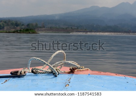 The front of the ship with a white rope moves towards the island with blue water in the Selorejo dam, Malang, Indonesia