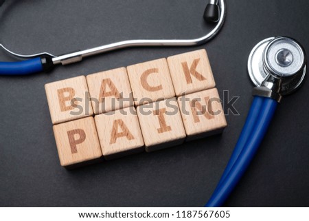 Wooden block form the word BACK PAIN with stethoscope. Medical concept.