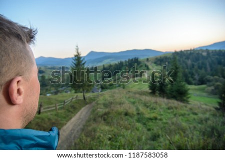 A traveler-photographer observes the sunset over the forest and mountains in the Ukrainian Carpathians