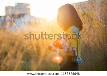 People side view,photographer woman take photo with old DSLR camera.Asian traveler female sightseeing with mirrorless camera against sunset backgroung.Travel and Photographer concept.