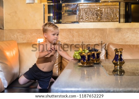 Small boy in a beautiful room at the table. Eating fruits